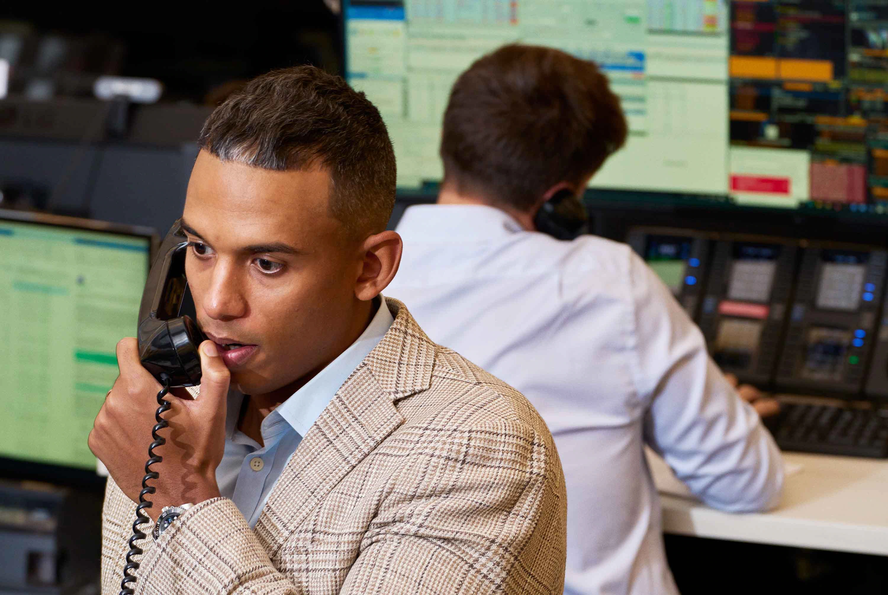 A person managing their finances on a laptop and phone, with a  Holloway card nearby